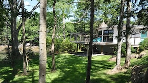 Ein Haus mit einer Terrasse mit Blick auf einen bewaldeten Bereich.