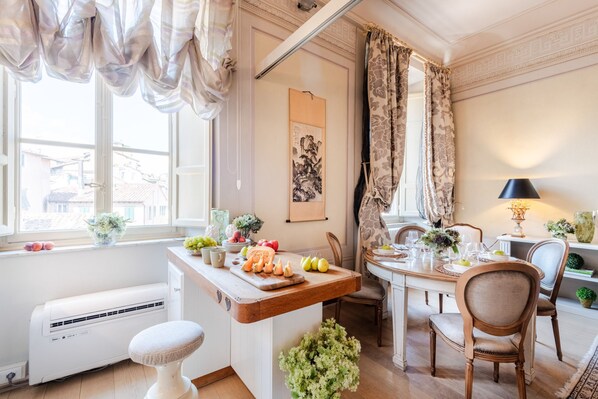 A well-lit dining area with a wooden table set for a meal, a white radiator, and a window with curtains. - Timeless Palazzo in Lucca (Lucca)