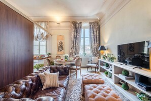 A living room with a leather sofa, ottoman, and a dining area with a table and chairs. - Timeless Palazzo in Lucca (Lucca)