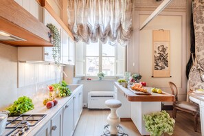 A kitchen with a gas stove, white cabinets, a wooden countertop, and a window with curtains. - Timeless Palazzo in Lucca (Lucca)