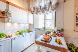 A kitchen with white cabinets, a wooden countertop, and a window with curtains. - Timeless Palazzo in Lucca (Lucca)