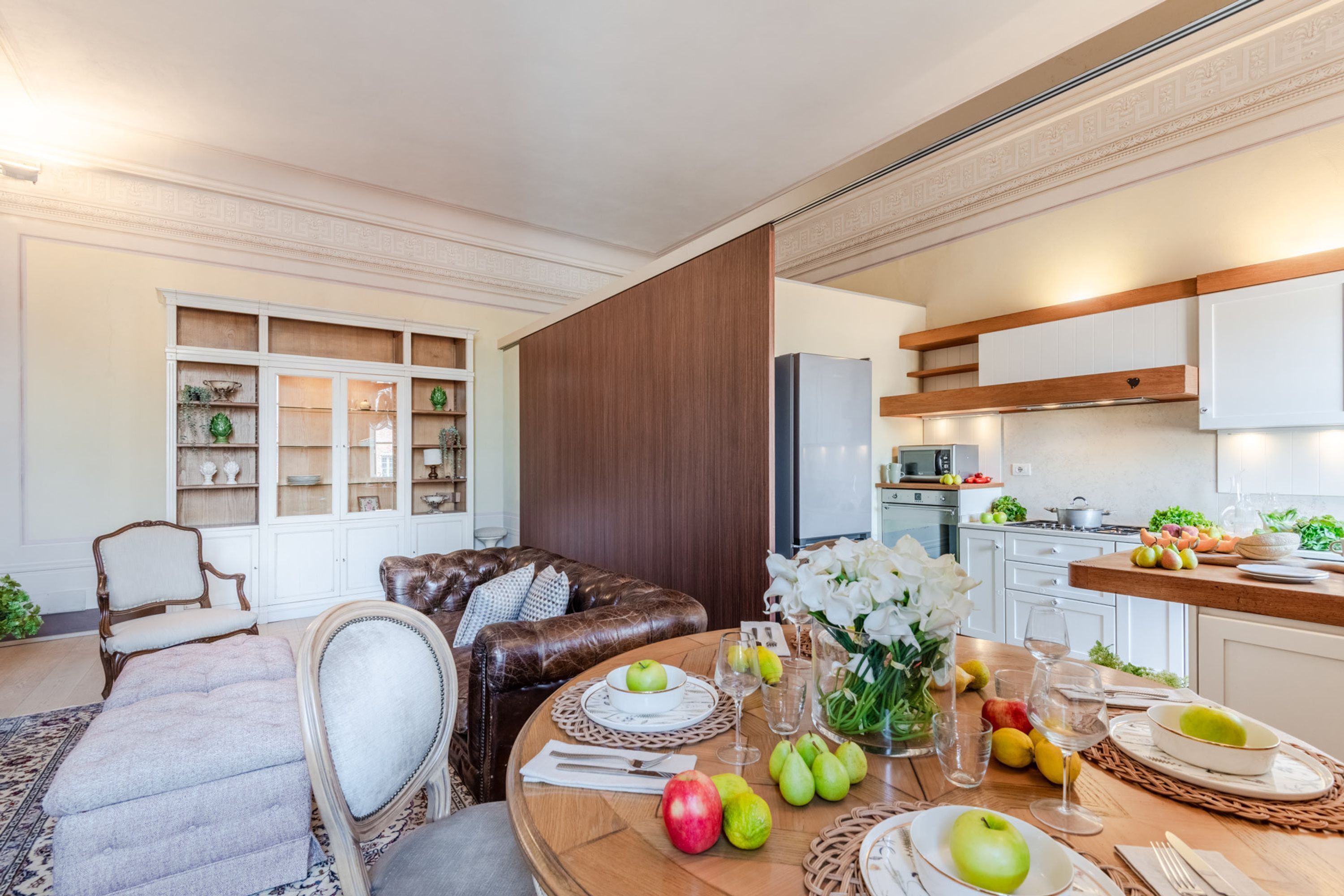Een moderne woonkamer met een eettafel gedekt voor een maaltijd, een leren bank en een decoratiemöbel.