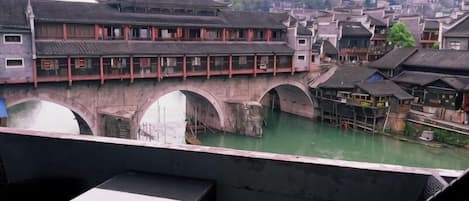 A traditional Chinese architectural style building with a bridge over a water body, likely a river, with multiple arches.