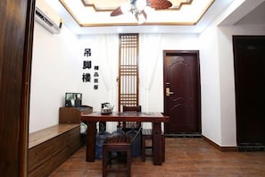 A room with a wooden table, chairs, a bench, a ceiling fan, a door, and a wall-mounted air conditioner. - yun shui jian jiangjing minsu (Fenghuang County)