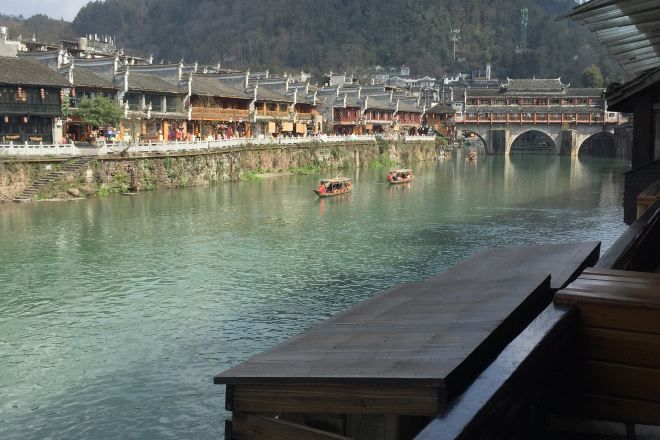 A traditional wooden building with a view of a river and a bridge.
