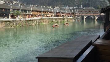 A traditional wooden building with a view of a river and a bridge.