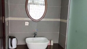 A bathroom with a white sink, a round mirror, and a kettle on the counter. - yun shui jian jiangjing minsu (Fenghuang County)