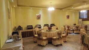 Uma sala de jantar com mesas e cadeiras redondas, um candelabro e decorações nas paredes.