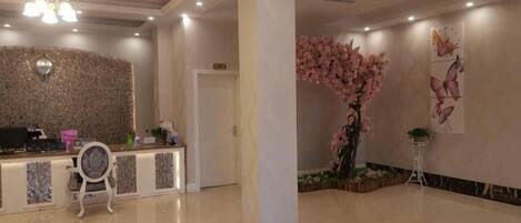 A reception area with a reception desk, a decorative wall, and a large floral arrangement.