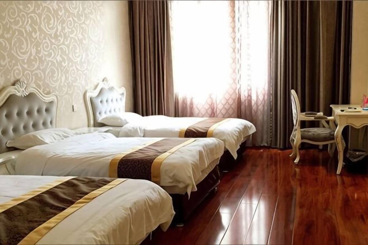 A hotel room with two beds, a desk, and a chair.