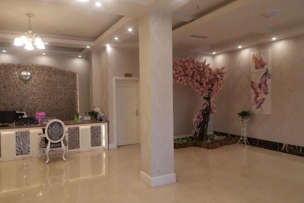A reception area with a modern desk, a chandelier, a column, and decorative wall art.