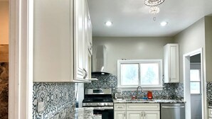 A modern kitchen with white cabinets, a stainless steel range, and a patterned backsplash. - Lincoln Ave Home By Naval Base! (North Chicago)