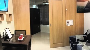 A compact living space with a dining area, a sofa, and a TV mounted on the wall. - Nice and Simple 1 Bedroom in Shell Residences (Pasay)