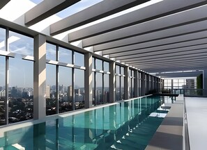 A modern indoor swimming pool with large windows and a city view. - WIDE (São Paulo)