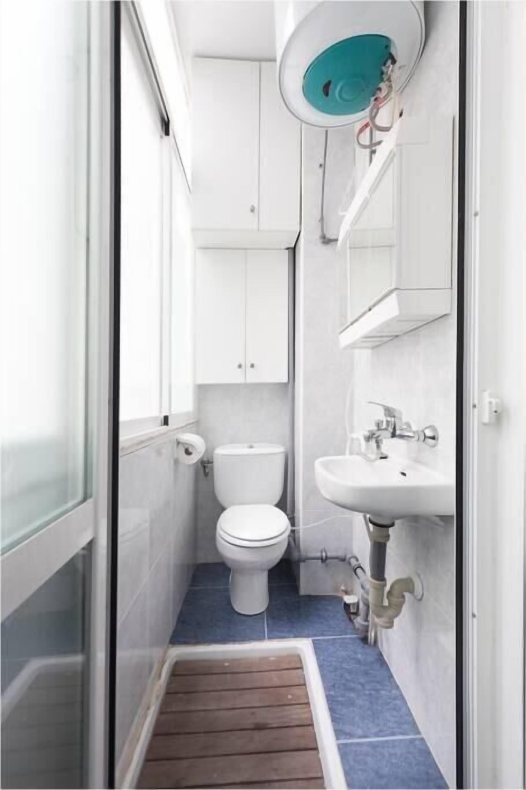 Ein kleines Badezimmer mit Toilette, Waschbecken und Schränken.
