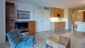A compact living space with a kitchenette, a dining area, and a seating area with a television and storage. - Apartment in Callantsoog Near Beach Access (Callantsoog)