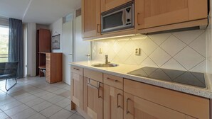 A modern kitchen with wooden cabinets, a microwave, a sink, and a countertop. - Apartment in Callantsoog Near Beach Access (Callantsoog)