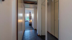 Un pasillo estrecho con una puerta al final que da a una habitación con ventana.