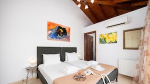 Ein Schlafzimmer mit einem großen Bett, einer Holzbalkendecke, einer Klimaanlage und zwei Bildern an der Wand.