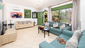 Ein Wohnzimmer mit einer Couch, einem Couchtisch, einem Fernseher und einem Gemälde an der Wand.