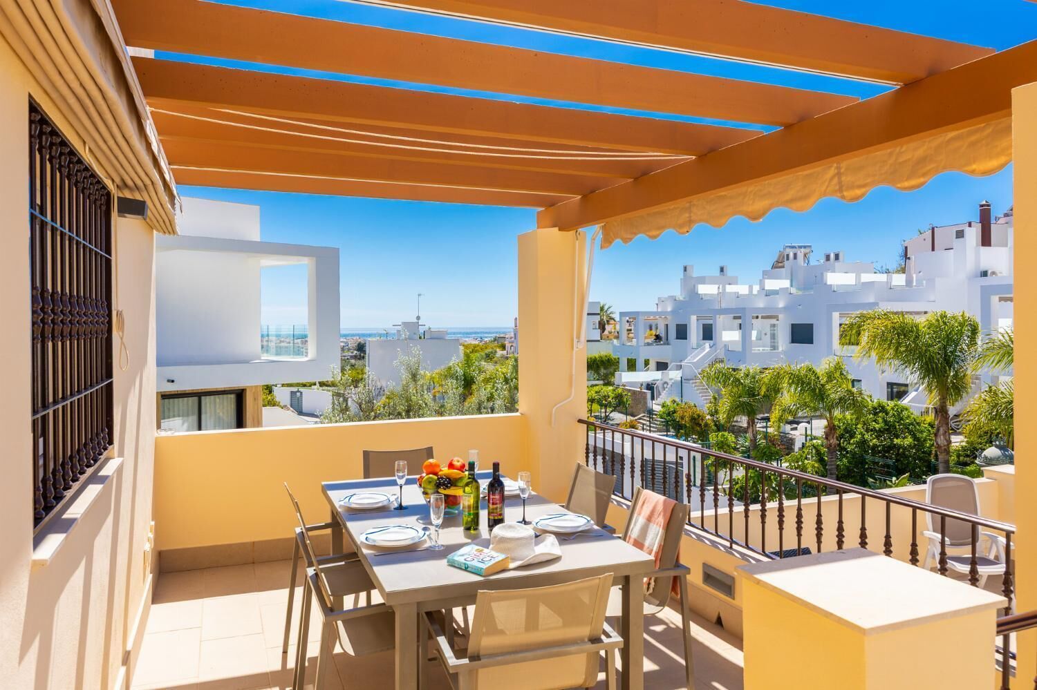 A balcony with a table set for two, a view of the city, and a clear sky.
