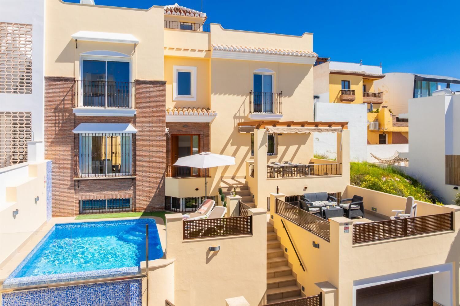 A multi-story hotel with a swimming pool, outdoor seating, and balconies.