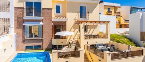 A multi-story hotel with a swimming pool, outdoor seating, and balconies.
