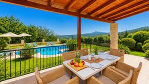 An outdoor dining area with a view of a swimming pool and mountains.