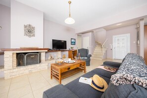 A living room with a fireplace, a television, a sofa, and a staircase leading to another level.