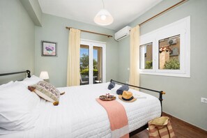 A bedroom with a bed, a bedside lamp, a window, and an air conditioning unit.