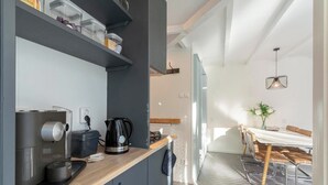 A modern kitchen with a coffee maker, kettle, and toaster. There is a dining area with a table and chairs. - Duinland 110 Bungalow in Sint Maartenszee (Sint Maartensvlotbrug)