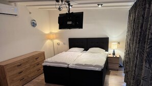 A bedroom with a bed, bedside tables, a TV, and a wardrobe. - Bungalow Near Sint Maartenszee Beach (Sint Maartensvlotbrug)
