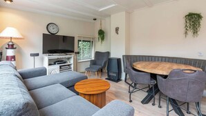 A modern living room with a sofa, a round wooden coffee table, a TV, and a fireplace. - Bungalow Near Sint Maartenszee Beach (Sint Maartensvlotbrug)