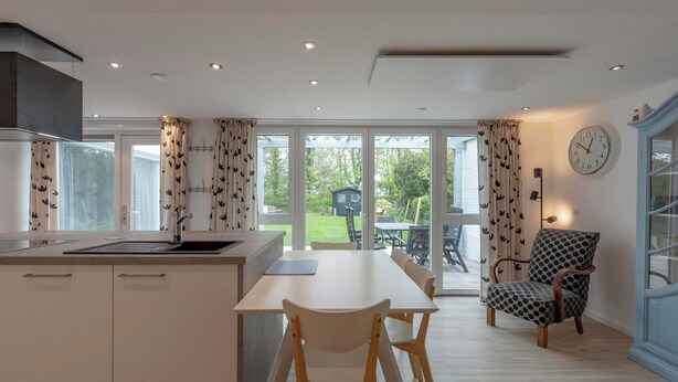 A modern kitchen with a dining area, large windows, and a view of the outdoors. - Duinland 146 for 4 Guests With Garden (Sint Maartensvlotbrug)