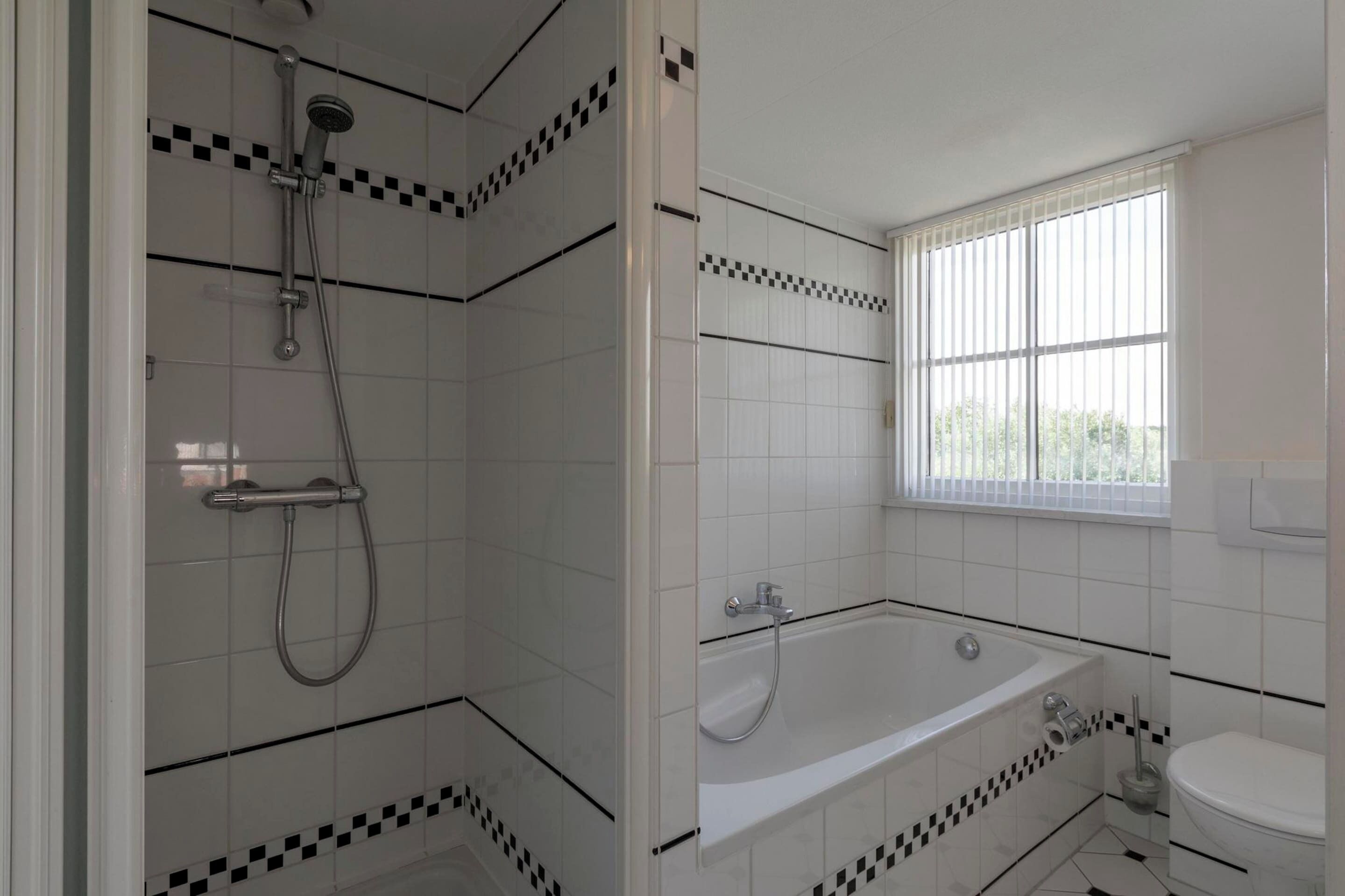 Ein Badezimmer mit Dusche, Badewanne, Toilette und einem Fenster.
