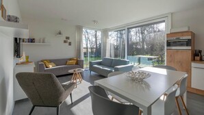 Una sala de estar moderna con un sofá, una mesa de comedor y una zona de cocina con horno.