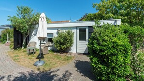 Een modern huis met een verharde oprit, een overdekt terras en een kleine tuin.