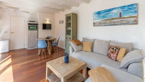 A living room with a sofa, a coffee table, and a dining area with chairs and a table. - Duinland 122 Bungalow foe 2-people (Sint Maartensvlotbrug)