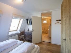 Une chambre à coucher avec un lit, une chaise, un téléviseur et une armoire en bois.