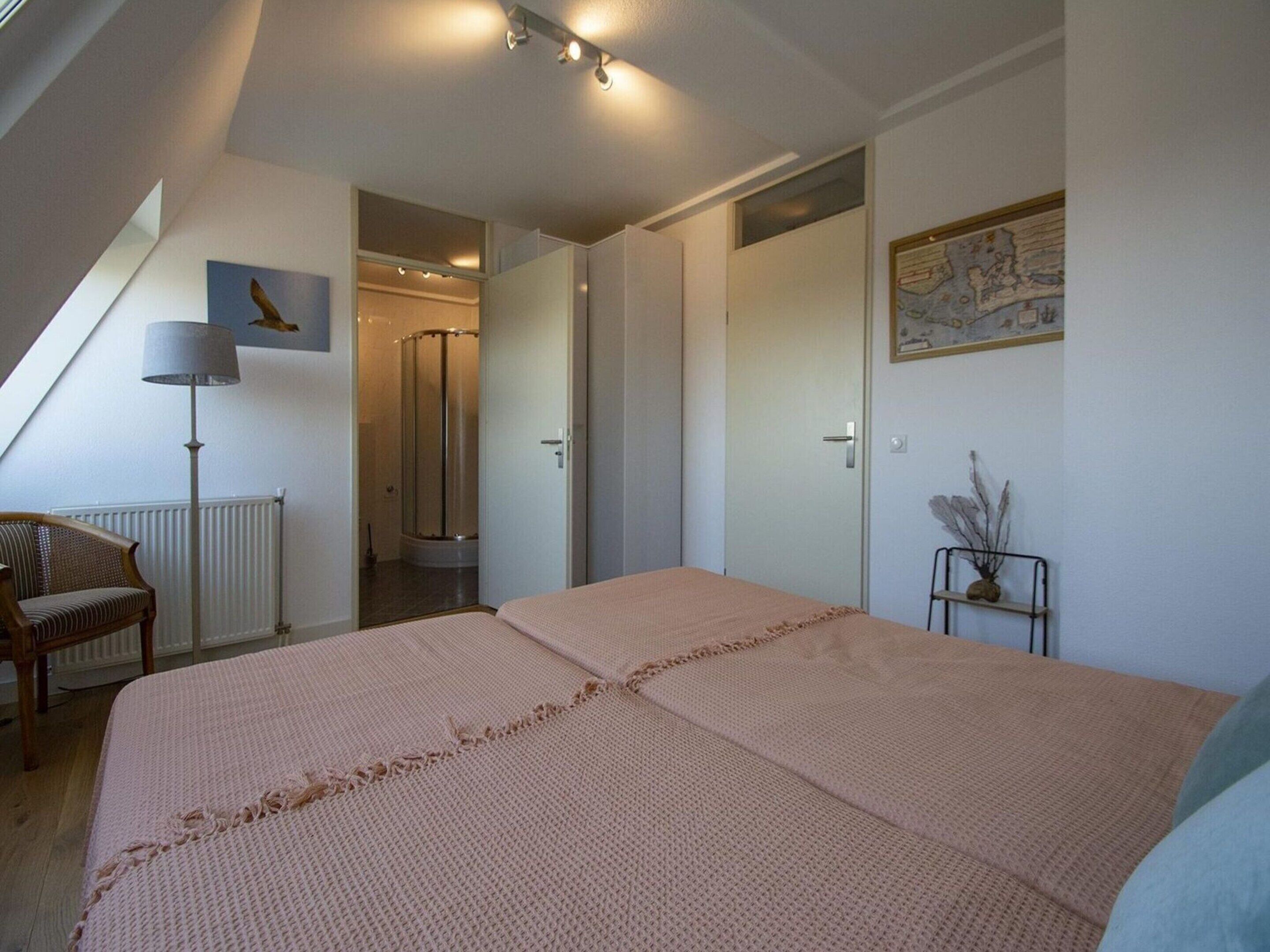 A bedroom with a large bed, a chair, a radiator, a shower, and a map on the wall.