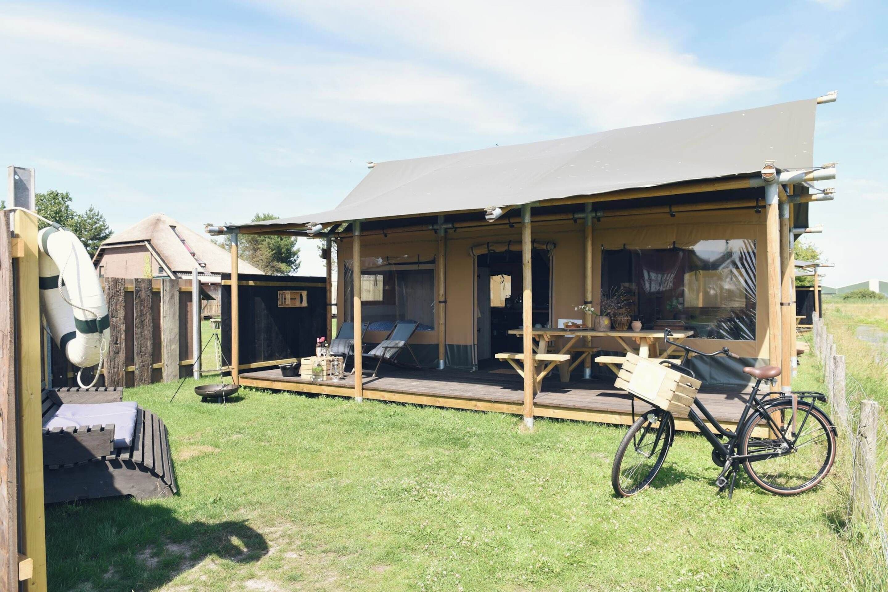 A wooden structure with a covered patio, a bicycle, and a picnic table.