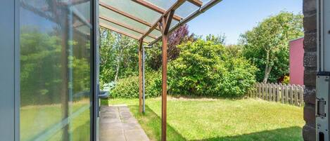 A covered patio area with a glass enclosure, a stone wall, and a wooden fence.