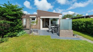 Ein modernes, zweistöckiges Haus mit Terrasse, Essbereich und Garage.