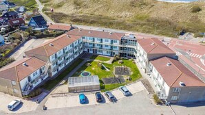 A multi-story hotel with a central courtyard, parking area, and a view of the beach. - Beach Apartment 35 for 4 Guests, Callanstoog (Callantsoog)
