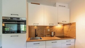 Una cocina moderna con armarios blancos, un horno de acero inoxidable, un lavamanos y una encimera de madera.