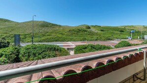 Vista desde una terraza en la azotea con vistas a una carretera, un paisaje verde y colinas al fondo.