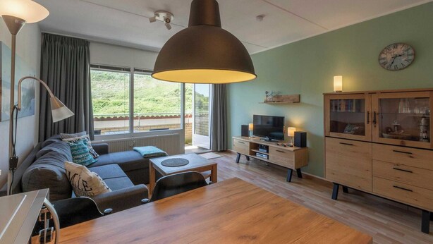 Una sala de estar moderna con un sofá, una mesa de comedor, un televisor y un aparador.