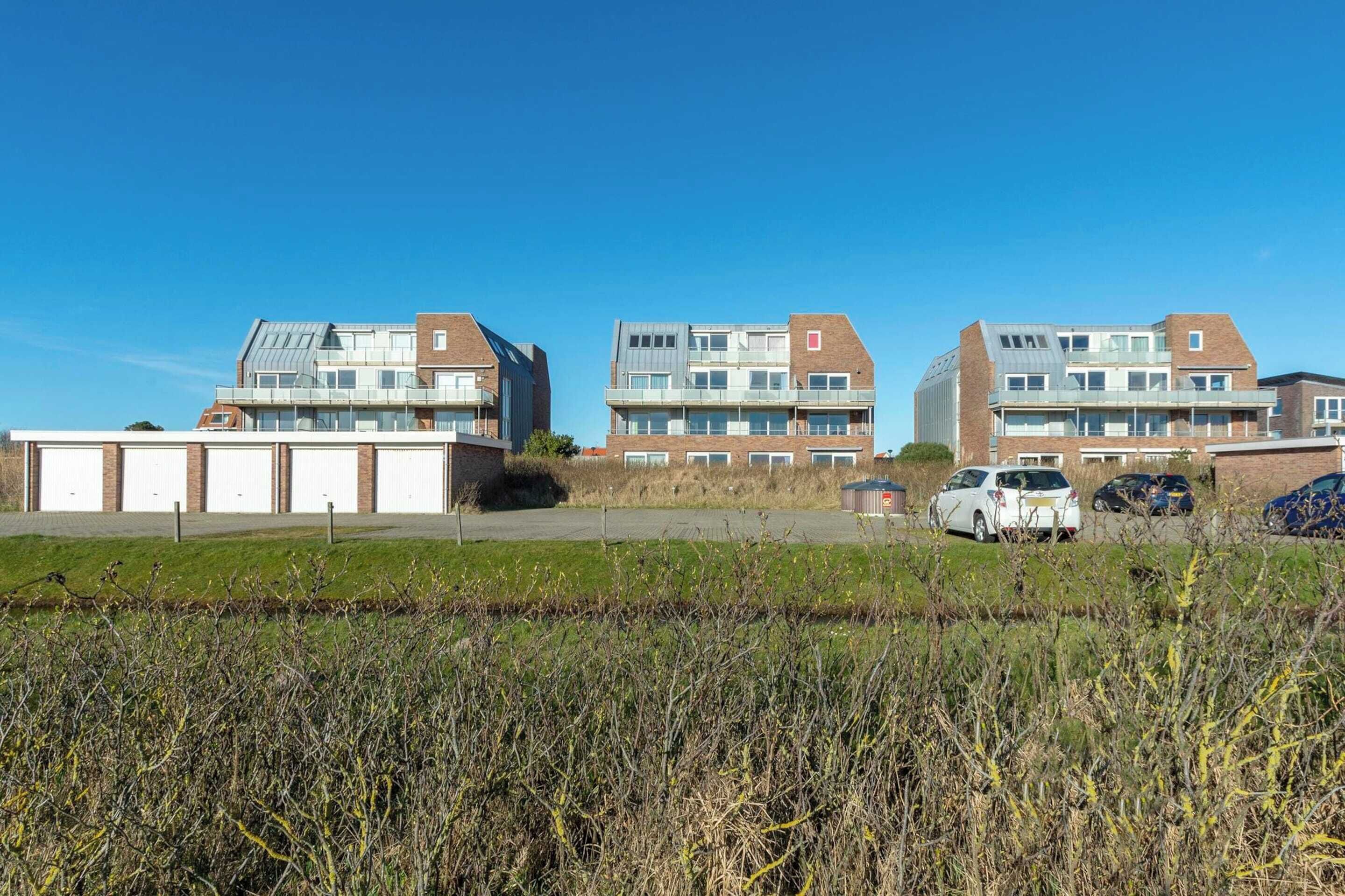 A residential building with multiple floors, large windows, and a flat roof.