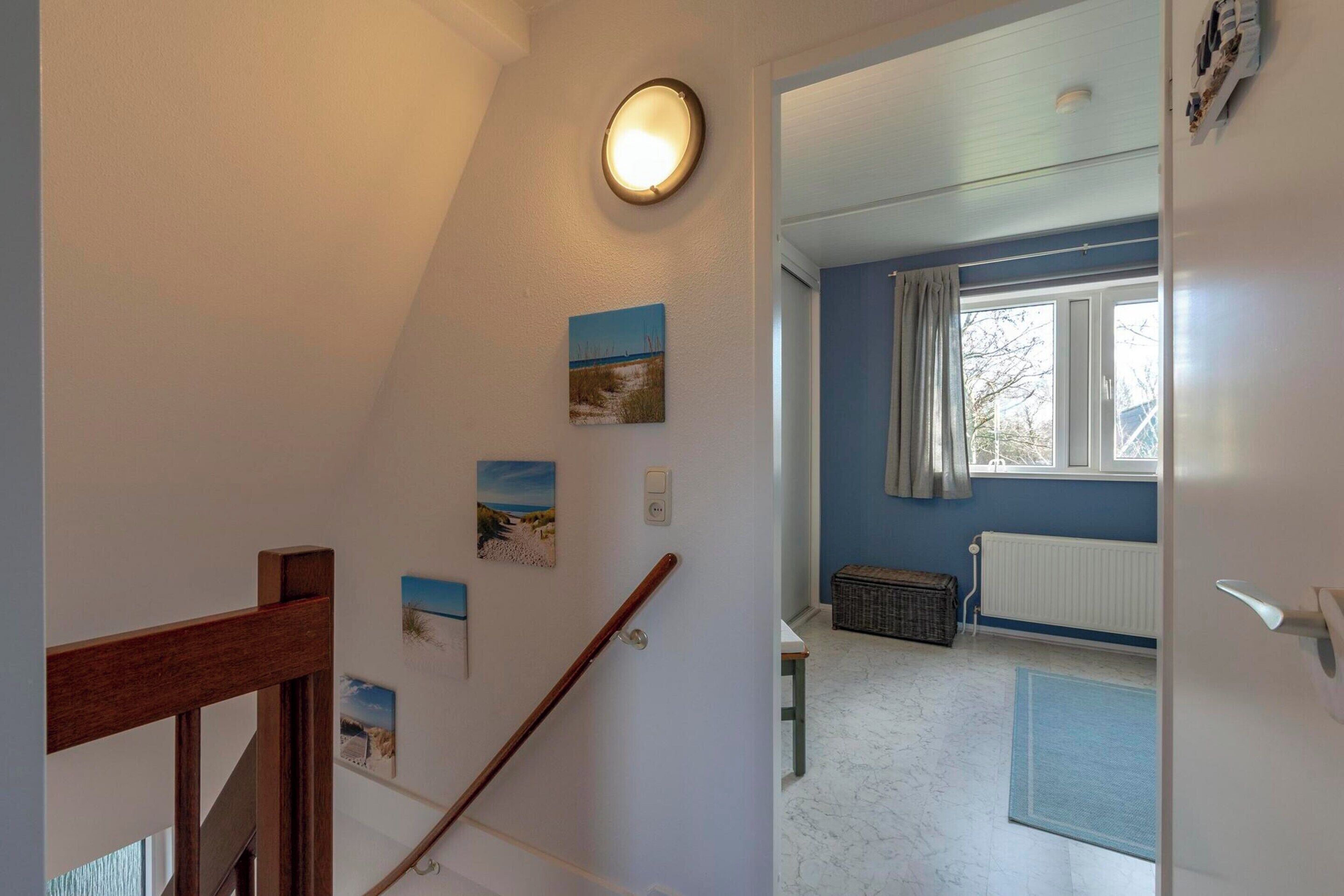 A staircase with a wooden handrail, a wall-mounted light, and several framed pictures.