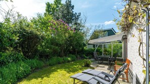 A backyard with a lawn, two lounge chairs, a table, and a pergola. - Holiday Home Near Dutch Beach With Pool (Sint Maartensvlotbrug)